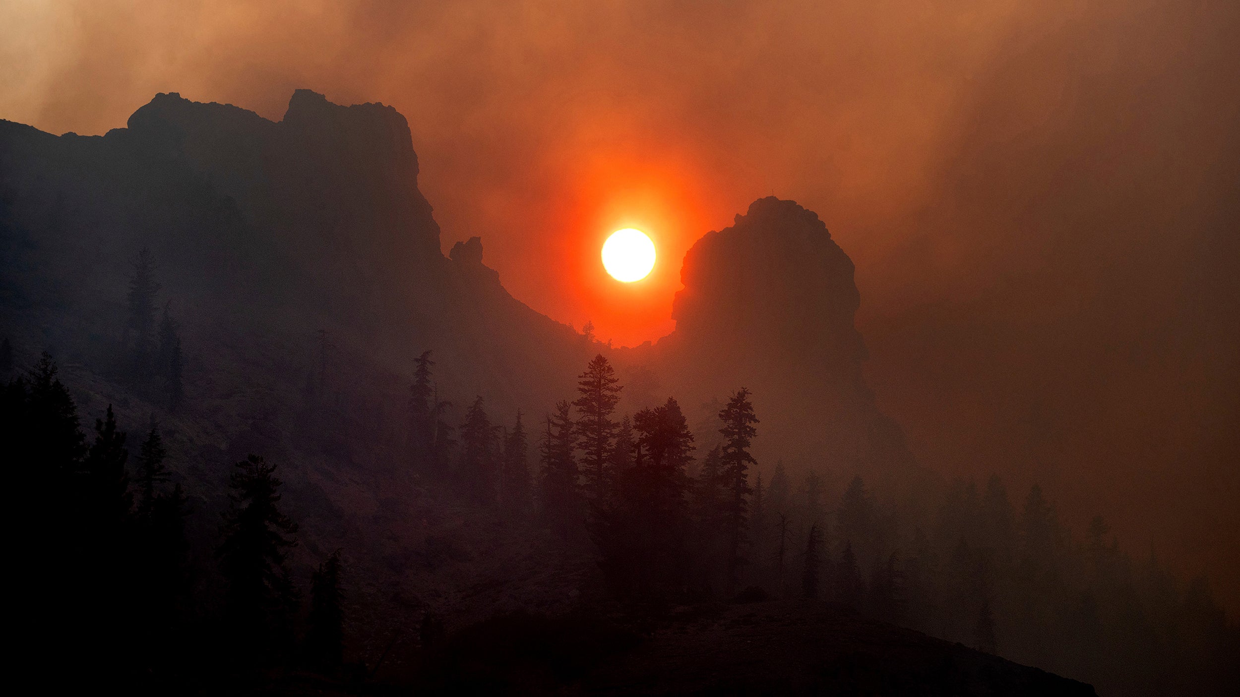 Caldor Fire creates smoky orange sky above Sierra Nevada mountains.
