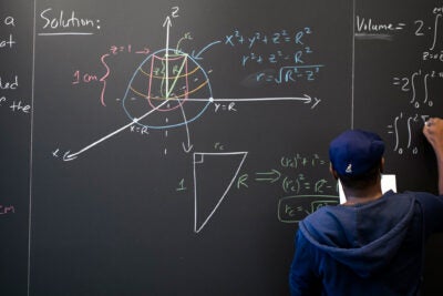 Hakim Walker writes on math lounge chalkboard.