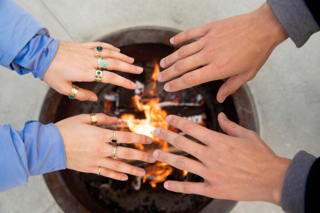 Students warm up their hands with a fire pit.