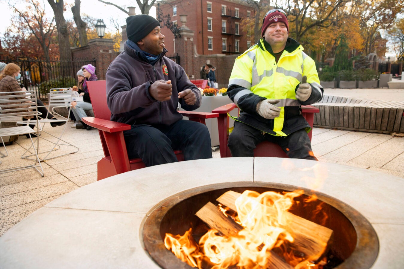 Cambridge firefighter John Barnard (left) and Mike Paskeywitz, a facility maintenance operation and campus service, warm their hands in the Fire Pit at Science Center Plaza.