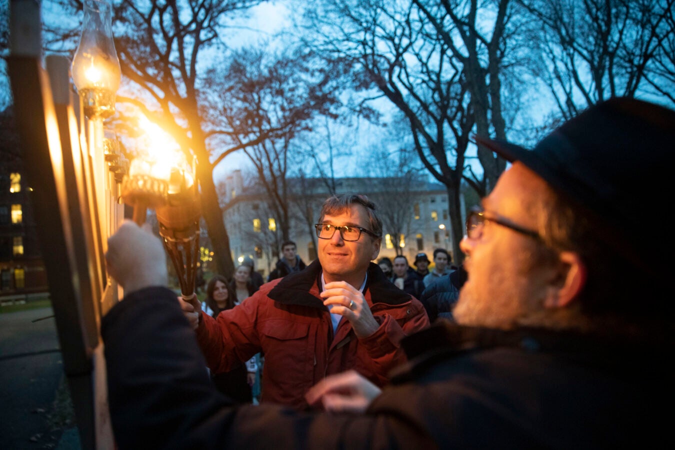Professor Jason Ferman of Kennedy School illuminates the candelabra of the main branch outside the Widener Library with Rabbi Hill Seesalki.