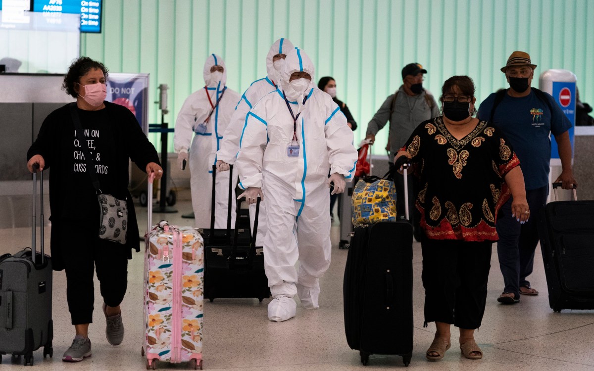 Flight crew members in hazmat suits walk through LAX.