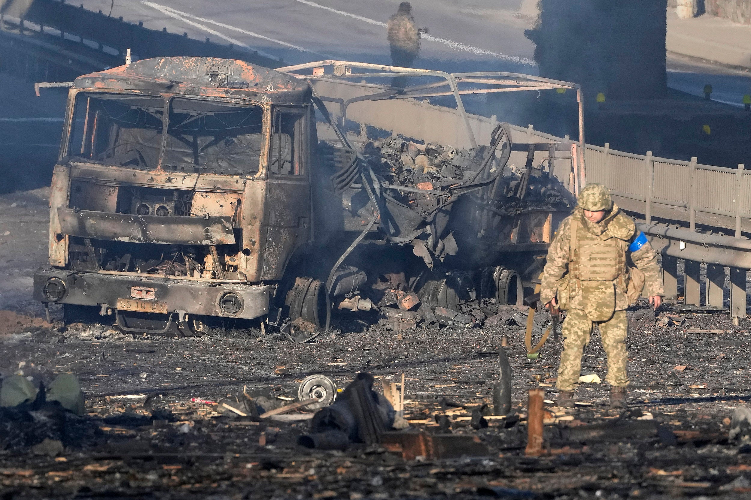 Soldier passes military truck burning in Kyiv, Ukraine.
