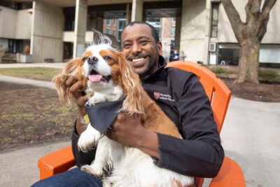 Anas El Turabi holds his cavalier King Charles spaniel Corgi in front of Mather House.