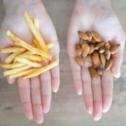 Choosing healthy or harmful food. Almond nuts or French fries in hand