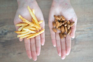 Choosing healthy or harmful food. Almond nuts or French fries in hand