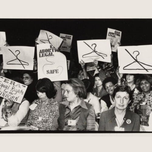 Women hold signs at International Women's Year conference in 1977.