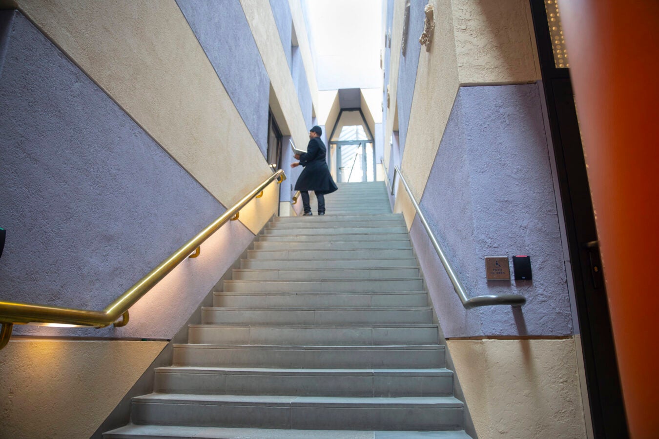 Precious Njong Tahnji walks up grand staircase inside 485 Broadway Street.