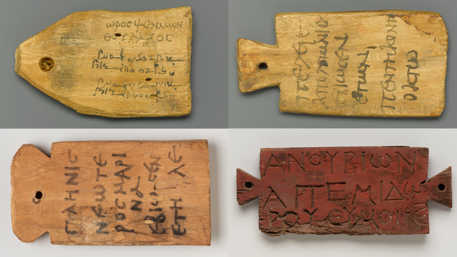 Four wooden mummy labels inscribed in ink in multiple scripts.