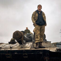 A Ukrainian soldier stands on a tank