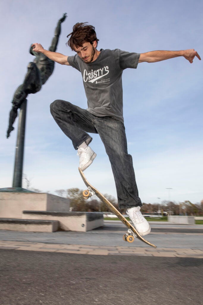 Joe Palma of Boston skates by the “Quest Eternal” statue temporarily stationed in Smith Field in Allston.
