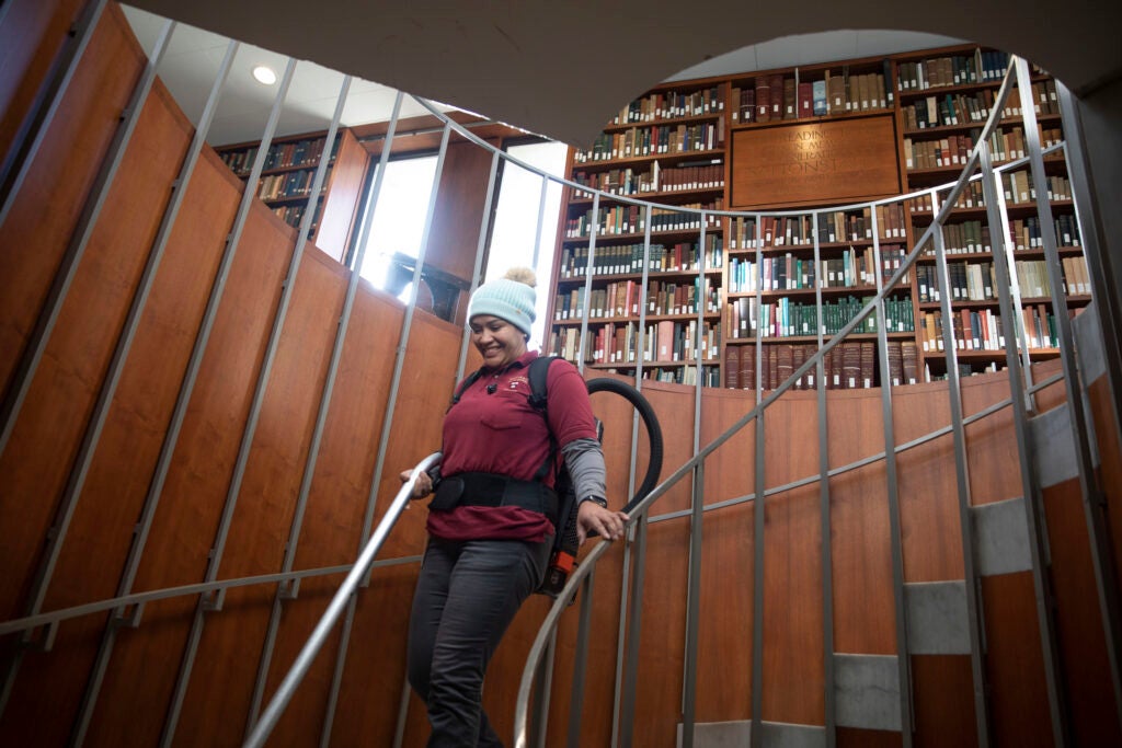 Evelyn Pena walks down the spiral staircase while cleaning the Leverett House Library.