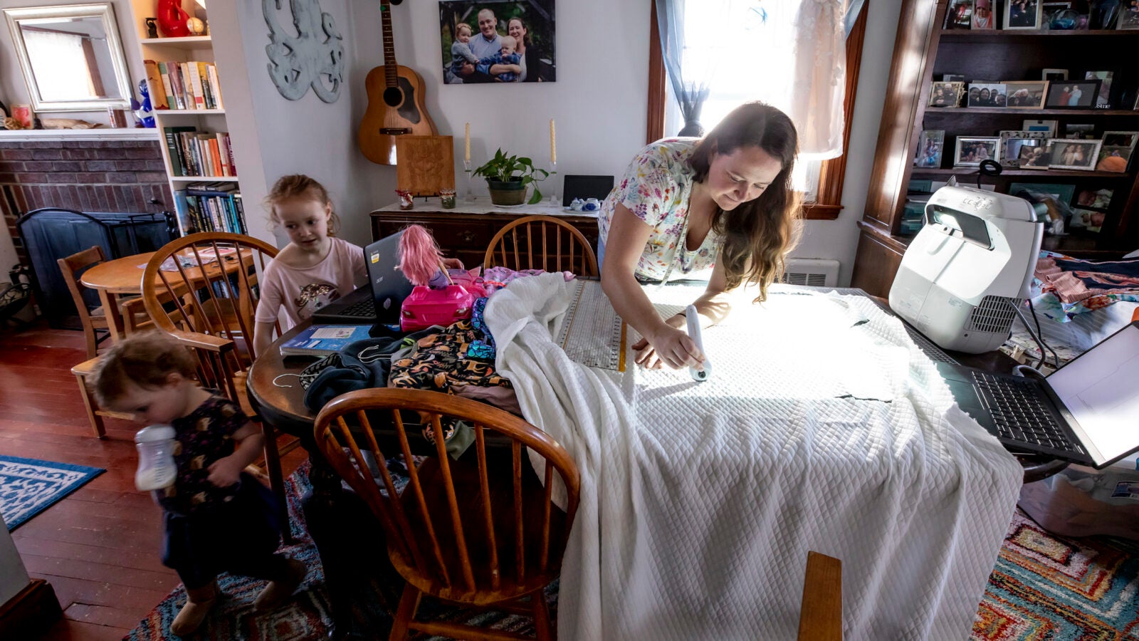 Kate Pease with daughters Ella and Coraline works on fabric arts in her dining room.
