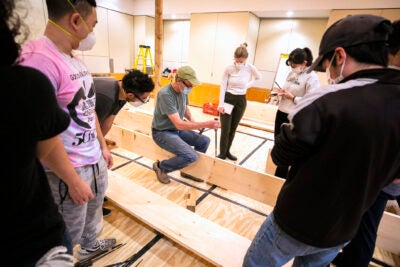 Students gather around instructor Douglas Brooks as they build a Japanese river skiff.