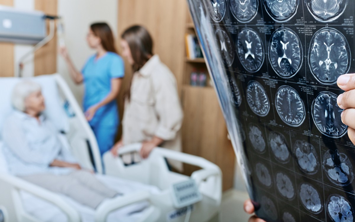 Doctor looks at brain scans with patient in background.