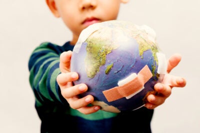 Child holding an Earth with bandages on it.