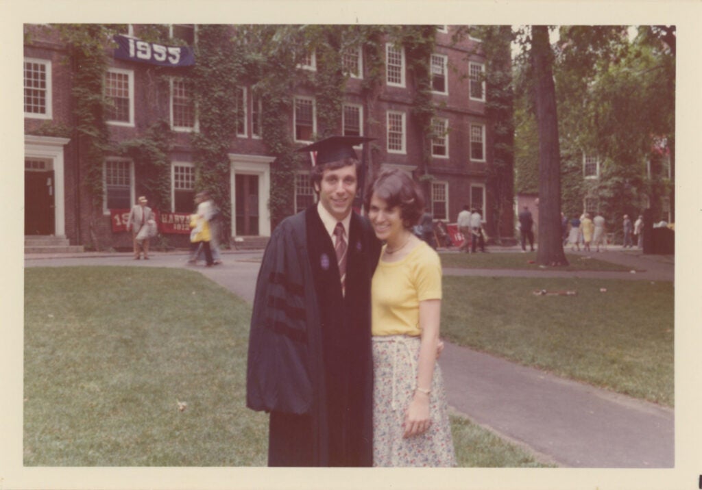 Polaroid of Larry Bacow in graduation cap and gown with wife Adele in Harvard Yard.
