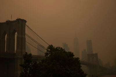 Orange haze over Brooklyn Bridge and New York City skyline.