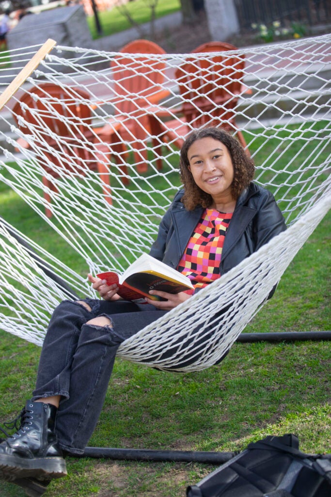 Maya Woods-Arthur ’23 studies a book while on a net hammock.