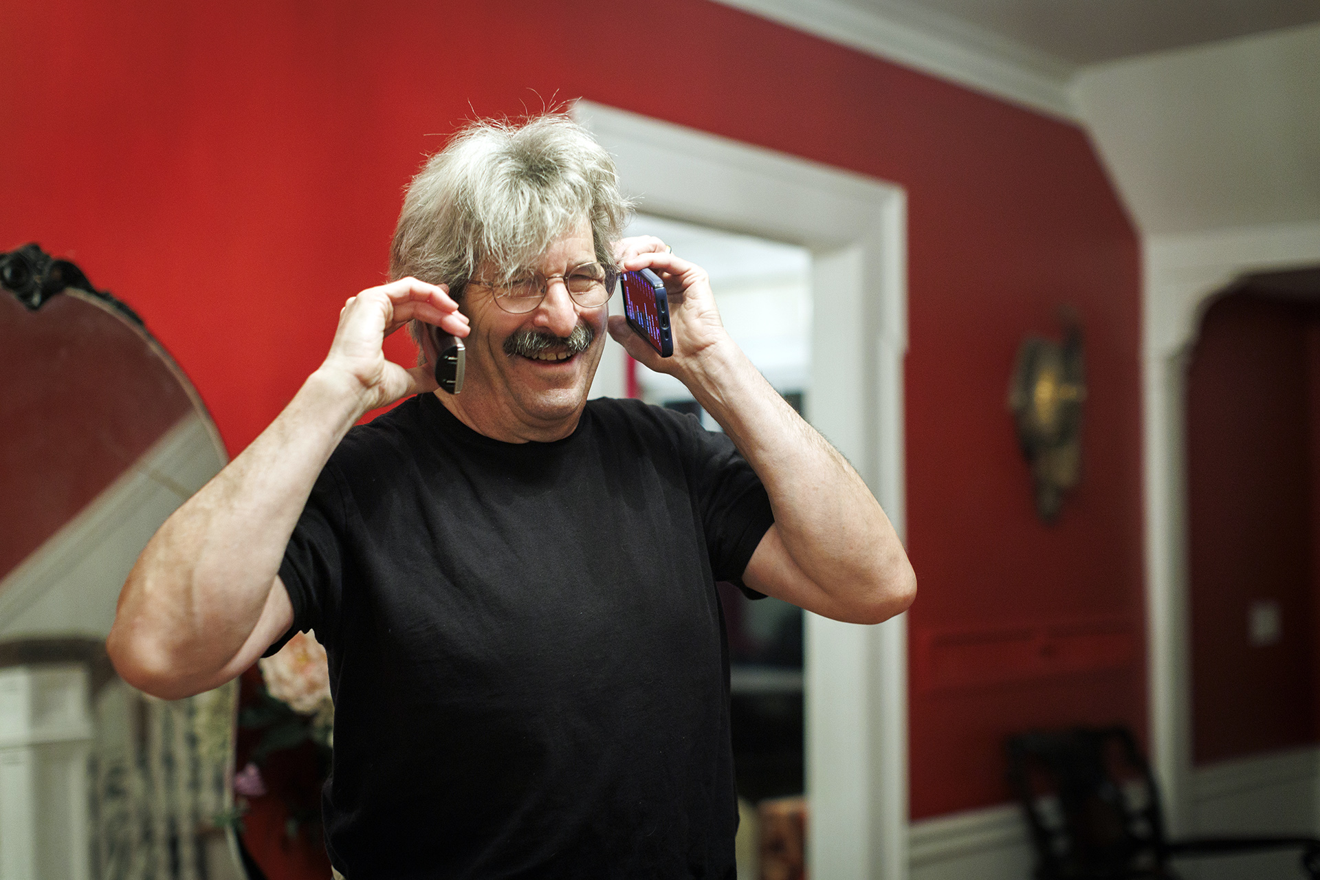 Gary Ruvkun holds a phone to each ear after learning he won the Nobel Prize.