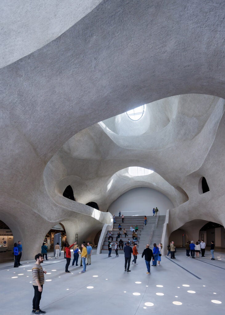 Visitors gather in open cave-like atrium bathed in light from skylights.