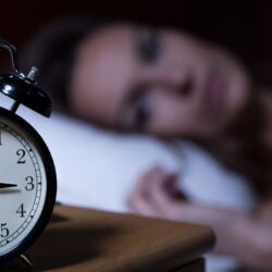 Woman not sleeping with clock showing 3 a.m.