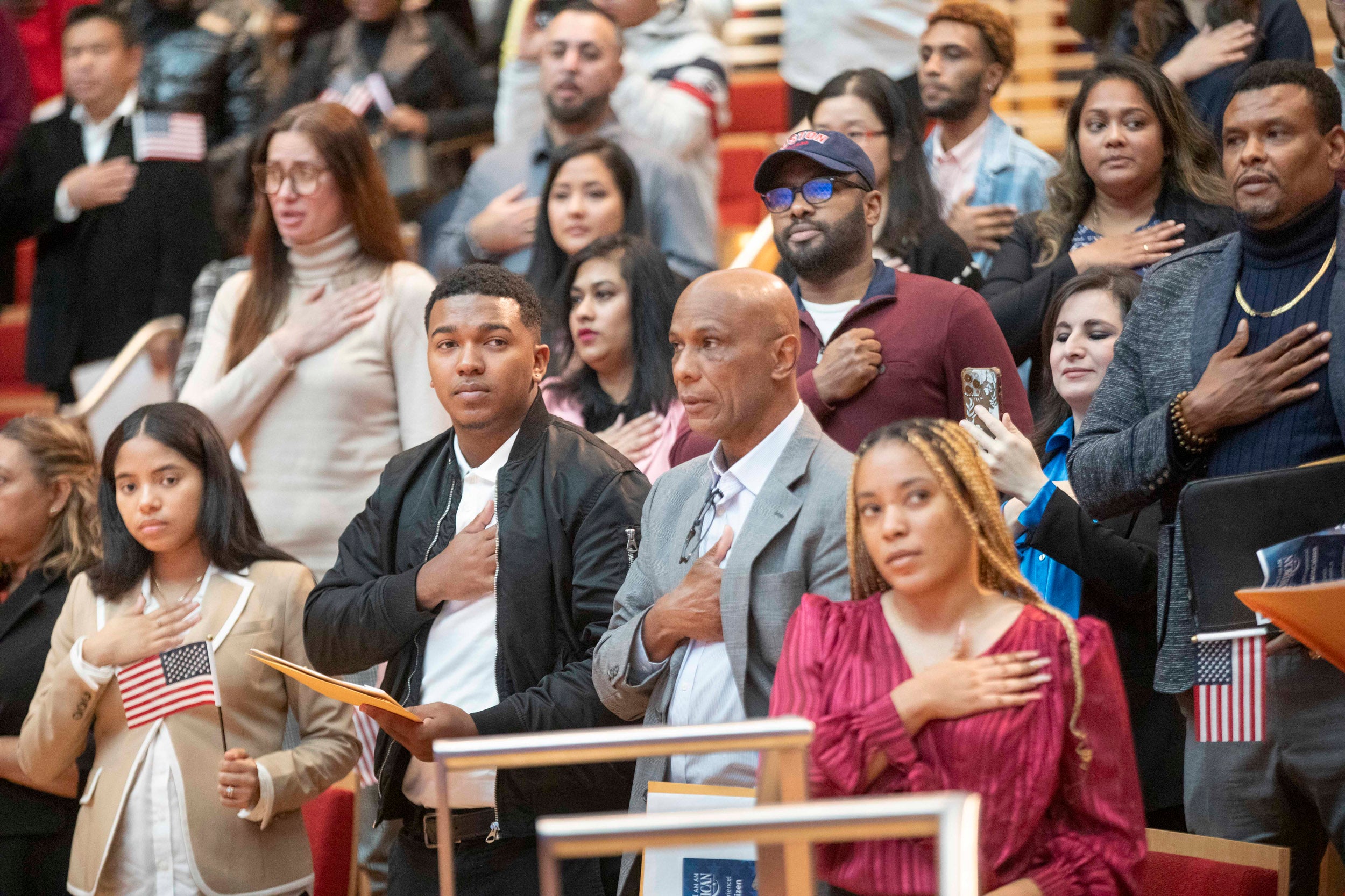 New citizens say Pledge of Allegiance during naturalization ceremony in Harvard's Klarman Hall.