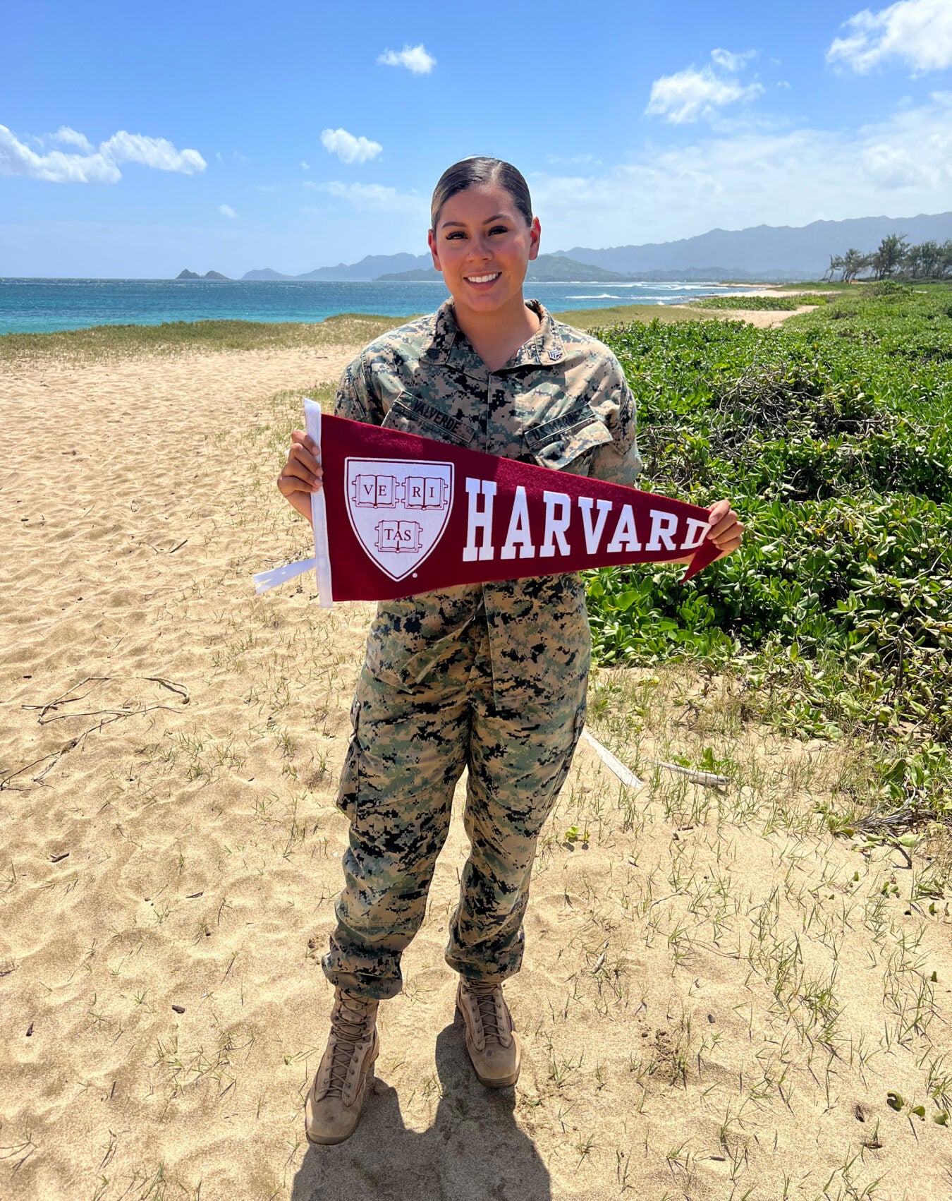 Vanessa Valverde holds Harvard banner while in uniform.
