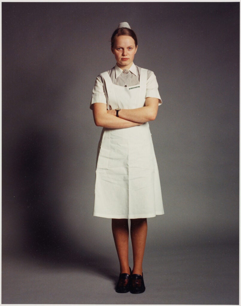 1970s photo of nursing student in uniform with arms folded.