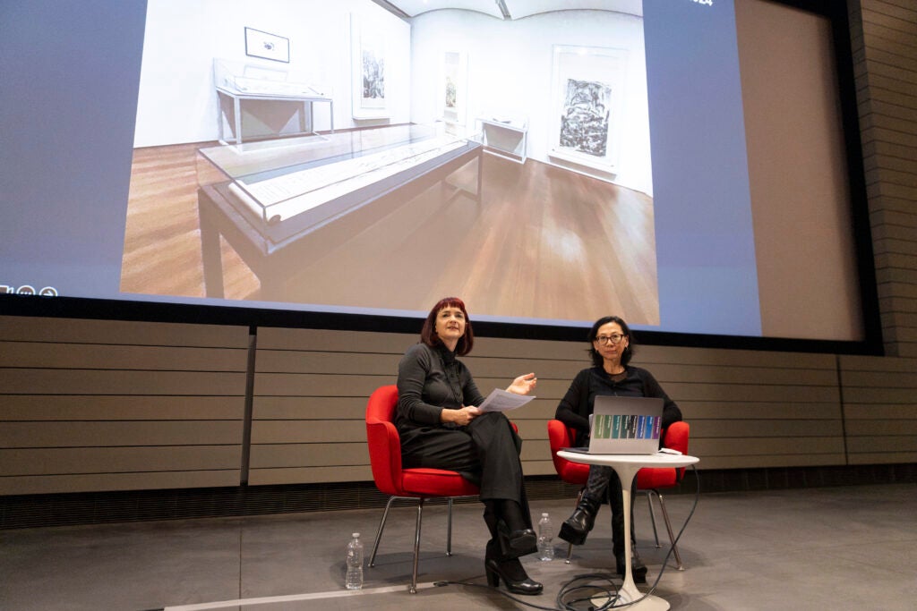 Sarah Laursen and Yu-Wen Wu sitting in front of a large screen displaying the  25-foot handscroll with Wu’s Google Maps directions cut and pasted in order.