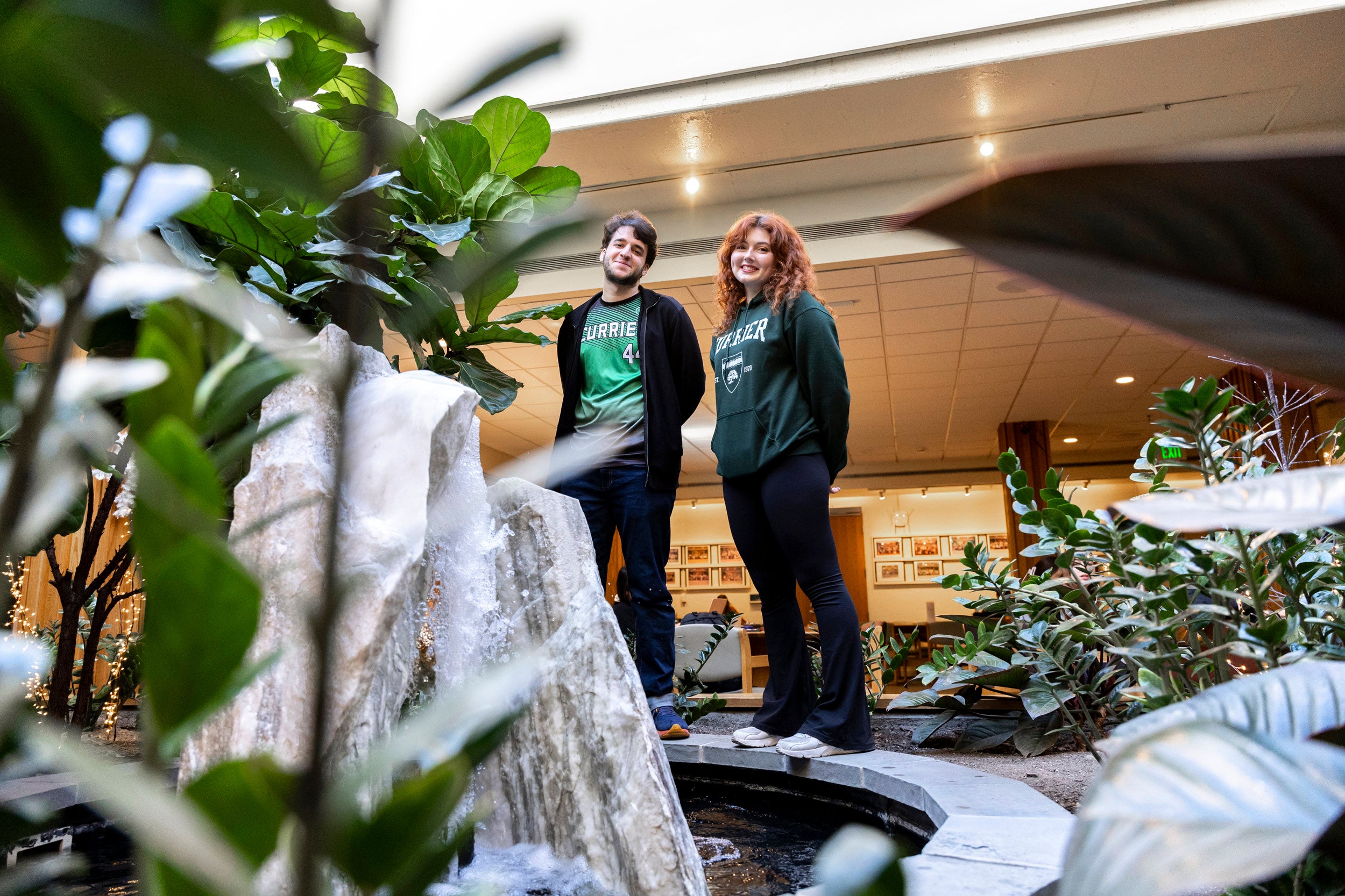Necati Unsal (left) and Sam Vitale stand within the fountain and greenery in the middle of the Currier House dining hall.