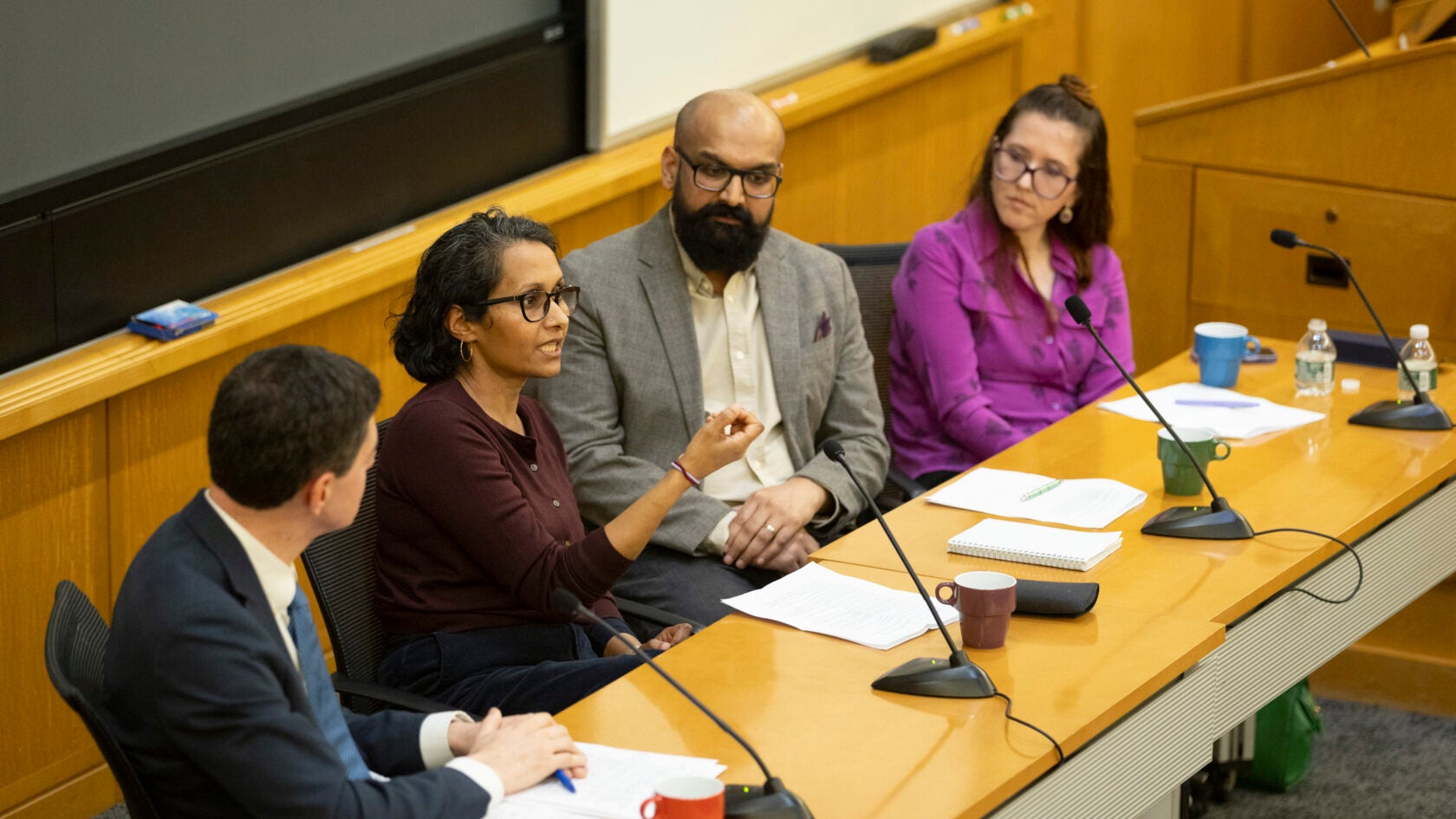 Eric Beerbohm (from left), Madura Rasaratnam, Mario Arulthas, and Kate Cronin-Furman sitting together in a lecture hall in front of microphones. 