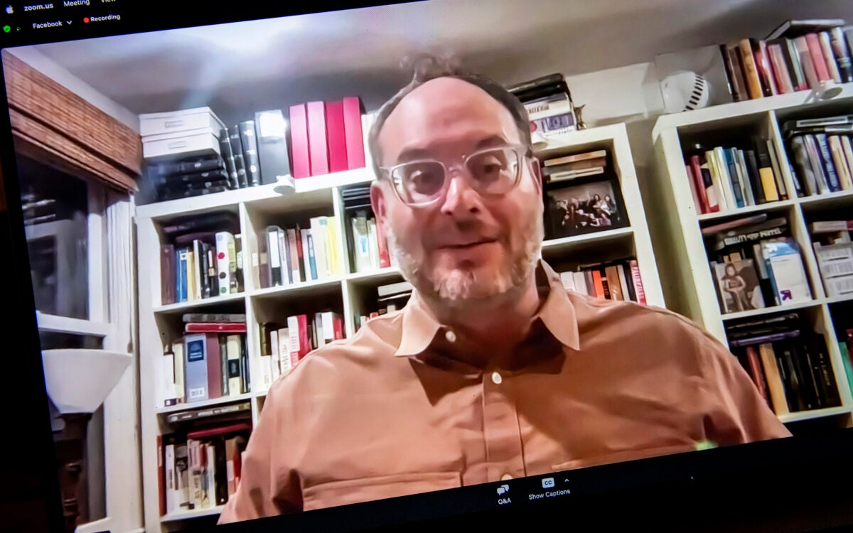 Franklin Foer wearing glasses and a button up shirt sitting in front of a bookcase.