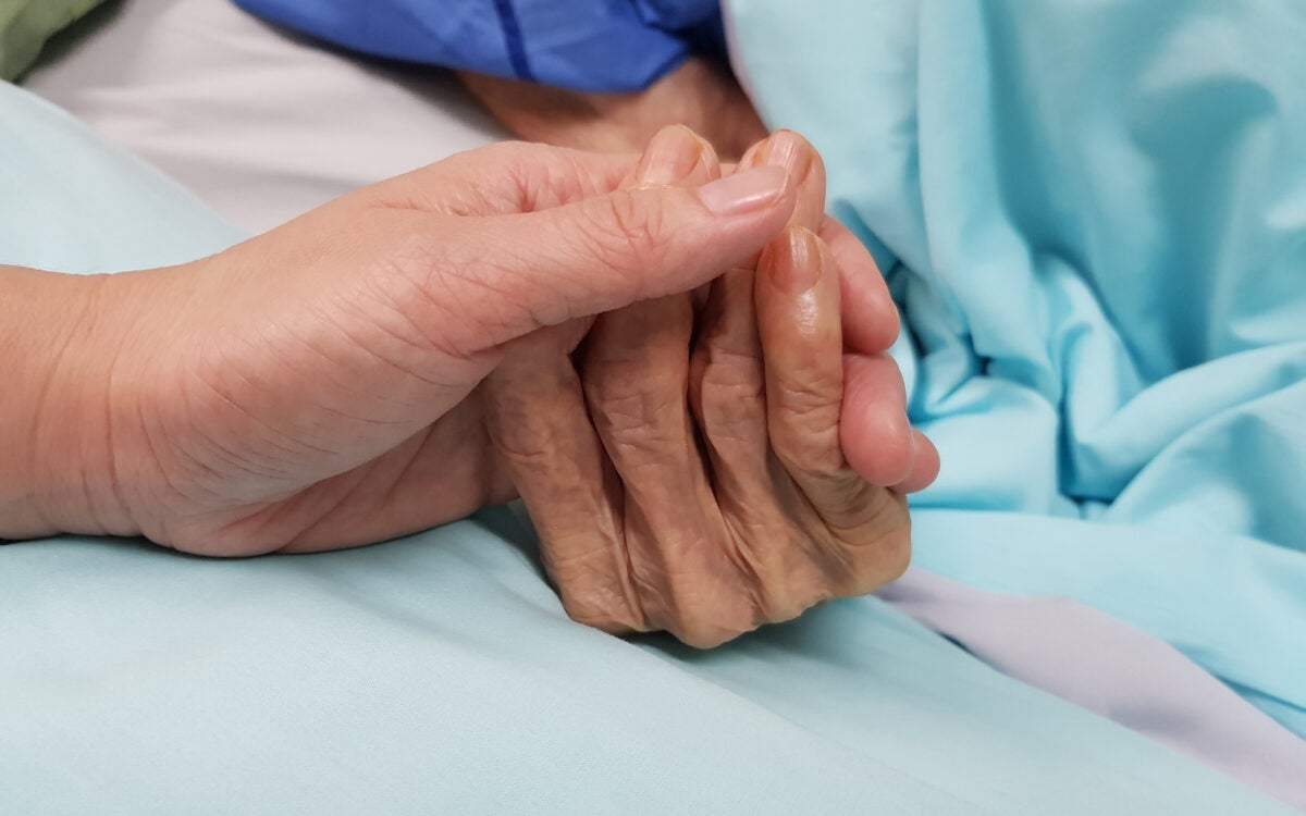 Detail of healthcare worker holding patient's hand.