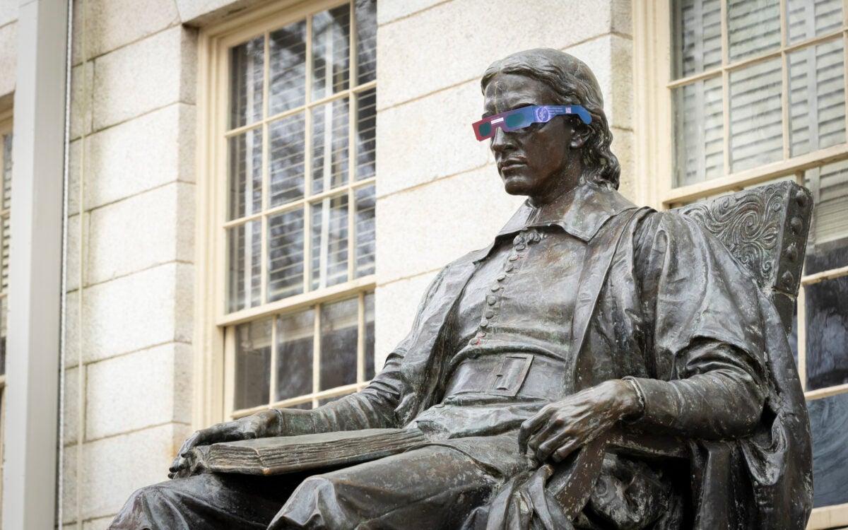 John Harvard statue wearing eclipse glasses.