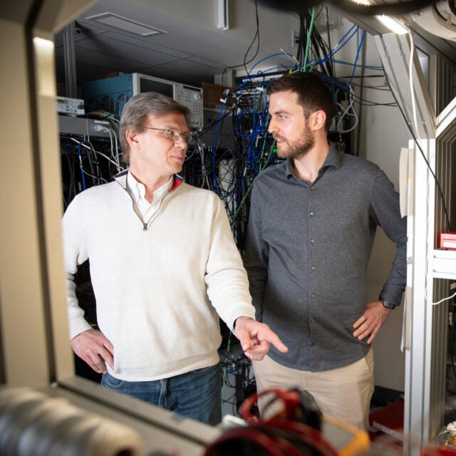 Mikhail Lukin (left) and Can Knaut stand near a quantum network node called a diamond silicon vacancy center.