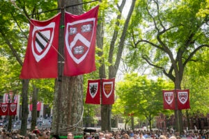Harvard School banners above a Commencement crowd.
