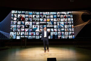 Matt Segneri, the Bruce and Bridgitt Executive Director of the Harvard Innovation Labs, stands in front of a screen filled with members of the i-lab community.