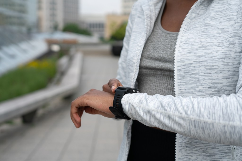 Close-up of a woman checking her smart watch while exercising.