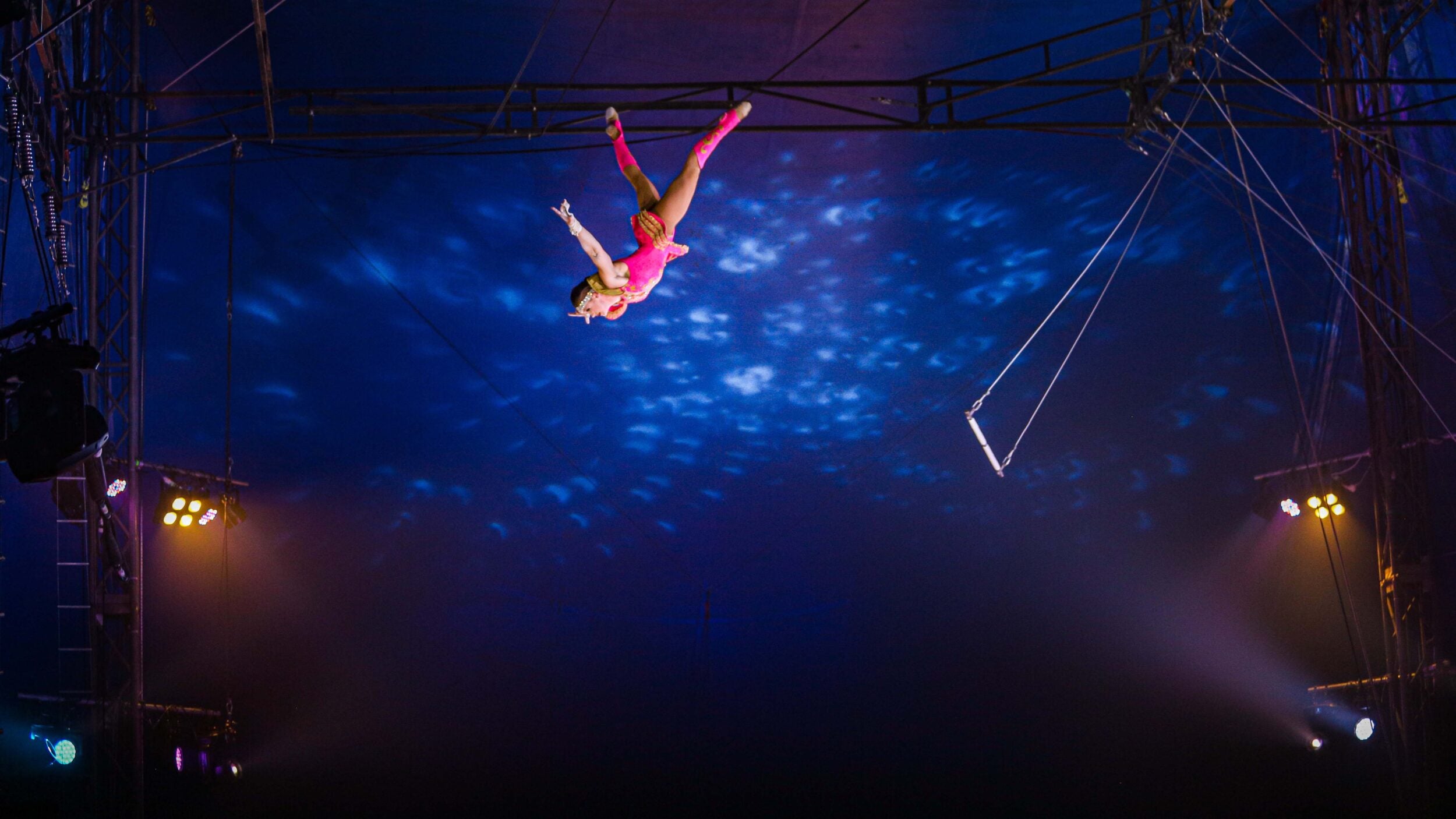 Trapeze artist Izzy Patrowicz flying through the during a circus performance. 