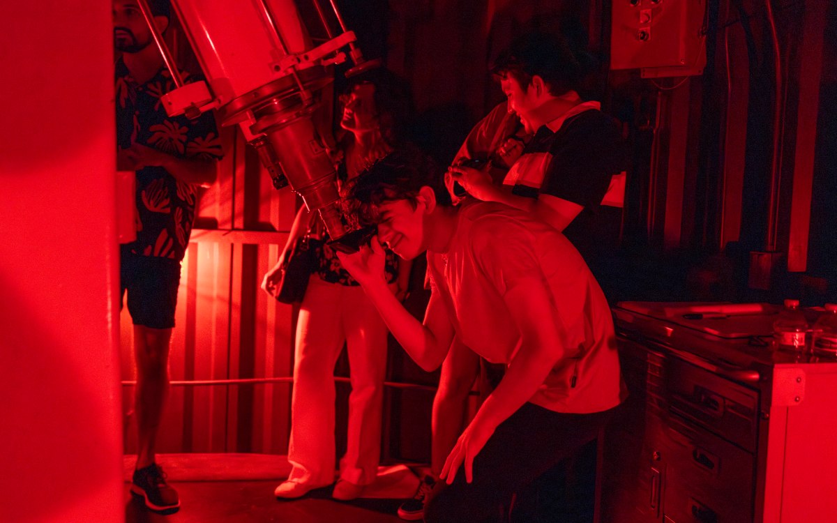 A man looks through a telescope.