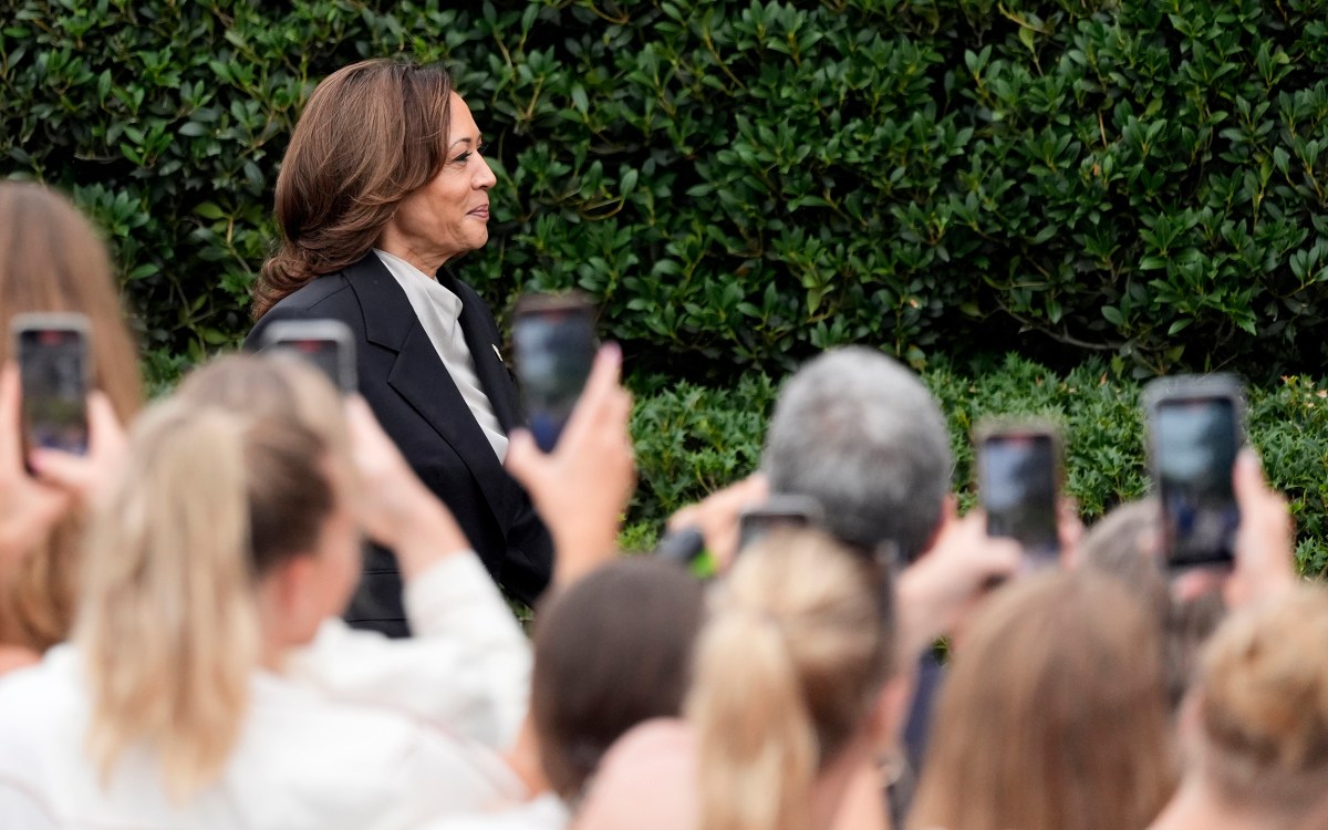 Kamala Harris walks by crowd gathered on White House lawn before speaking at an event.
