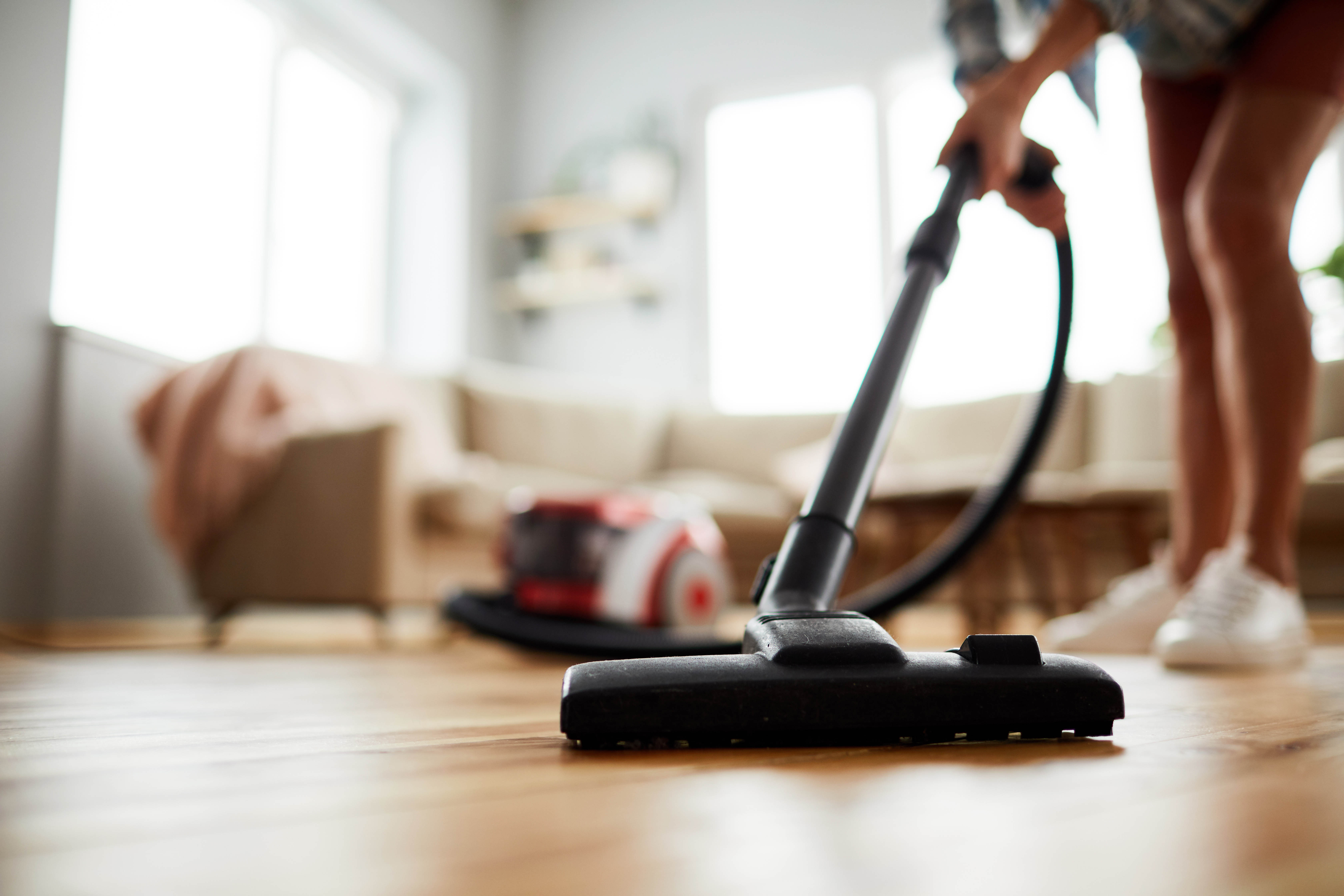 A person vacuums the floor of a home.