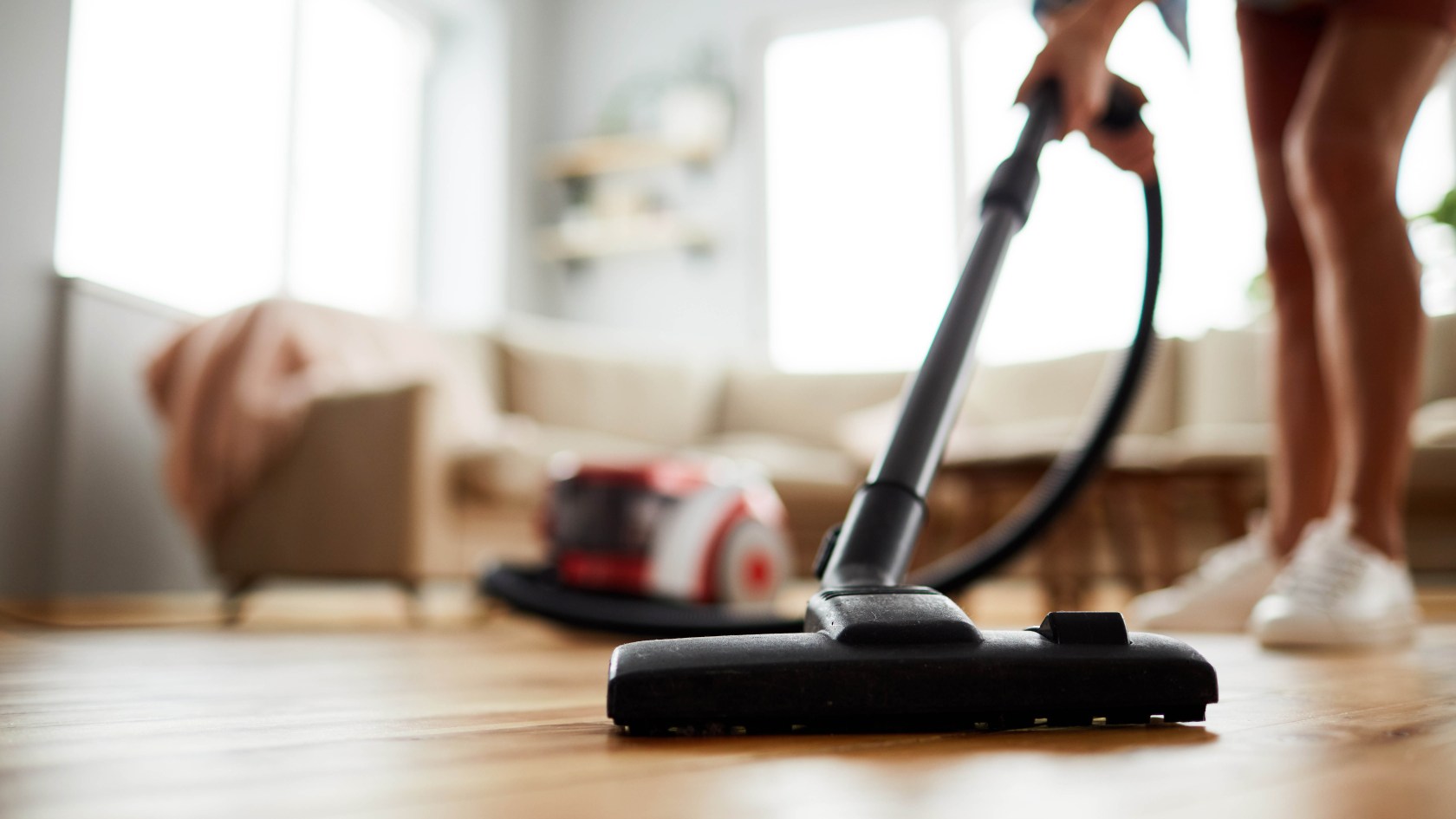 A person vacuums the floor of a home.