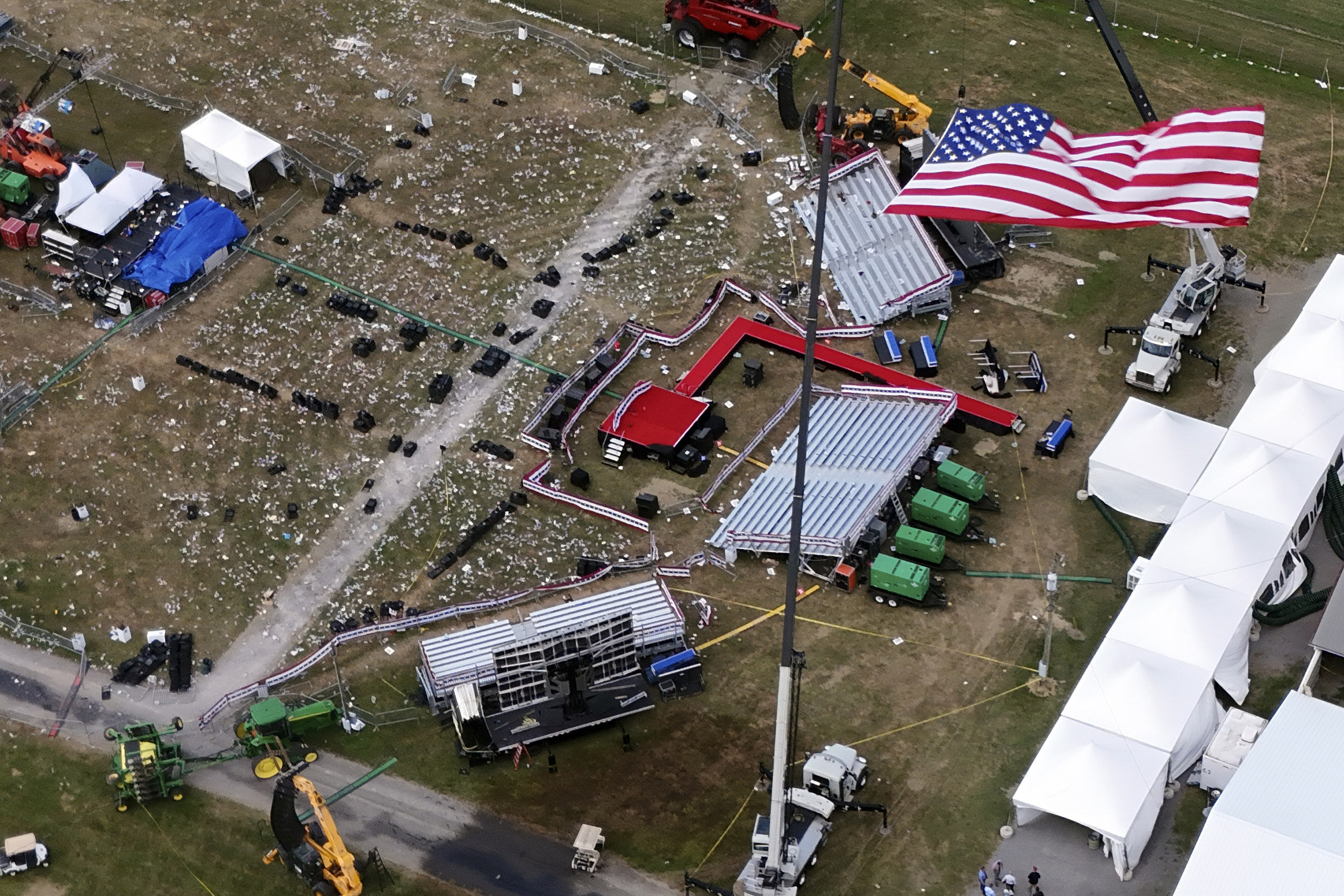 American flag flies in foreground of aerial view of Trump rally site days after attempted assassination.