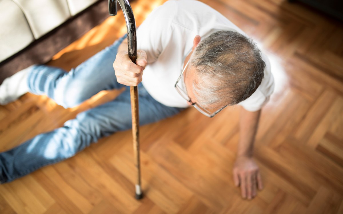 Older man with cane has fallen on the floor.