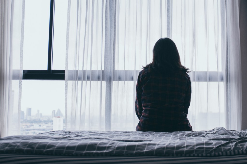 woman sitting on bed alone