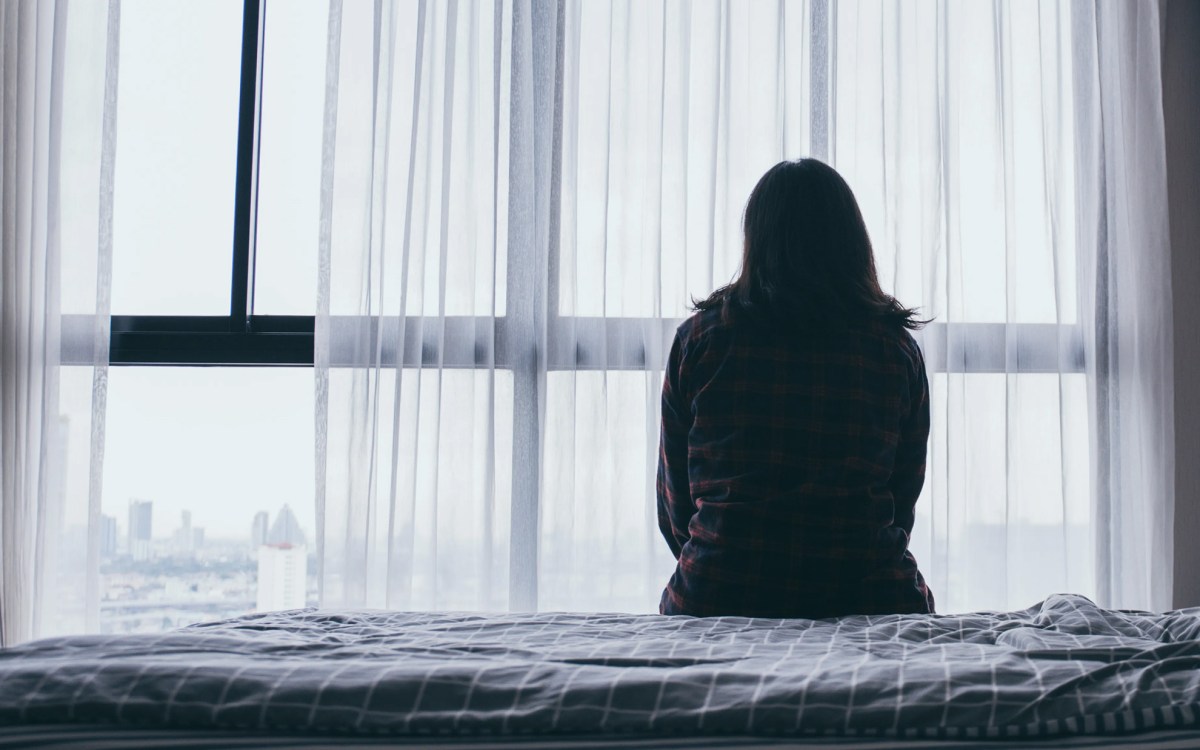 Sad woman sitting on a bed.