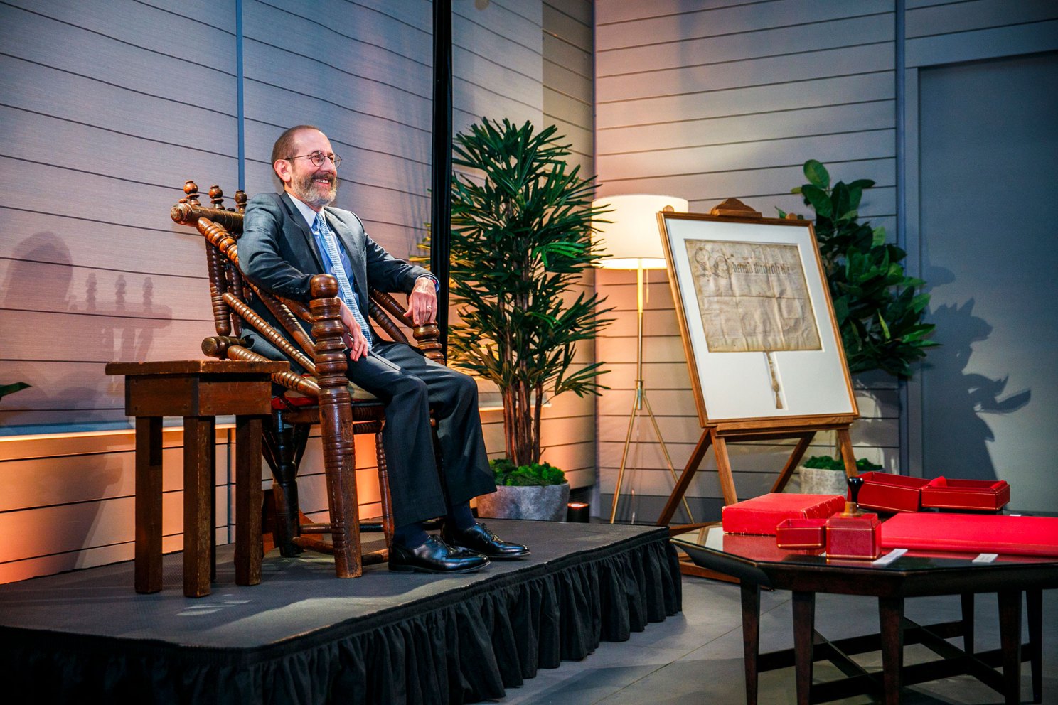 Garber sits in the Holyoke Chair with the other Harvard Insignia on display including the Harvard Charter during the event.