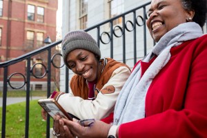 Emmanuel Enan Gachogu Muriuki (left), a first-year, and Sheila Thimba, Dean of Administration and Finance, share a Kenyan joke on the steps of University Hall in Harvard Yard.